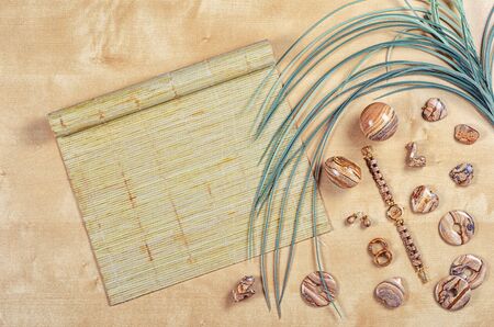 Flat lay different picture jasper items on wooden background with palm leaf and bamboo sushi rolling mat. Top view semi-precious stone jewelry concept.の写真素材