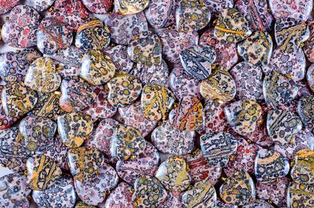 Many heart-shaped semi-precious stones of leopard skin jasper as backgroundの写真素材