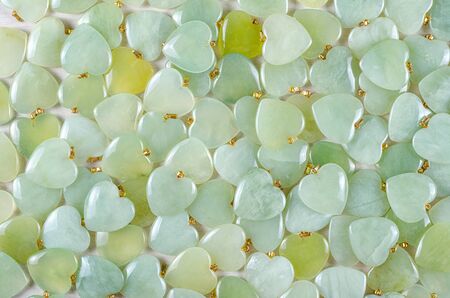 Many heart-shaped semi-precious stones of butter jade as background