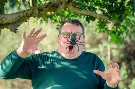 Middle-aged man undergoes a panic attack encountering a spider when strolling in the garden.の写真素材