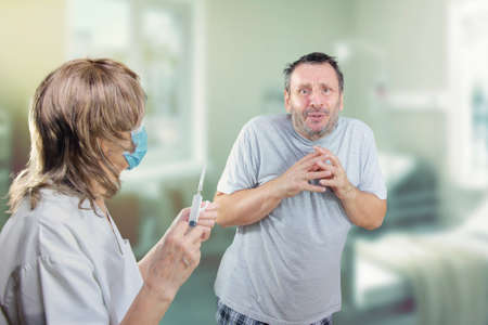 Mature man passes out while seeing a nurse with a syringe nearby. He suffers from trypanophobia.の写真素材