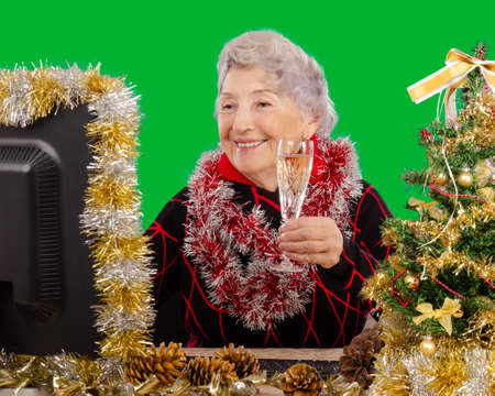Due to the coronavirus pandemic, a senior adult woman is celebrating Christmas Eve with her family via a video messenger on the Internet.の写真素材