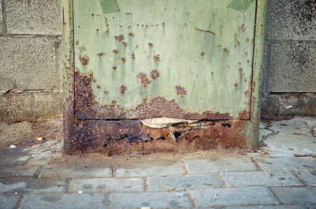 The acid in a dog's urine damages a green color mail storage box on a sidewalk.の写真素材