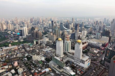 Panorama of Bangkok from a height. Many skyscrapers of different architecture, with domes and spiers on top. Small buildings are also closely built. In the distance, the city disappears in a haze.の写真素材