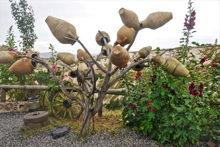 Pigeon Valley in Cappadocia. Clay pots and old wooden wheels hang on the branches of a dry tree....