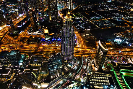 Night Dubai from above. Bright skyscrapers, glowing highways, multi-colored illumination of houses and streets. There is a beautiful tower in the center.のeditorial素材