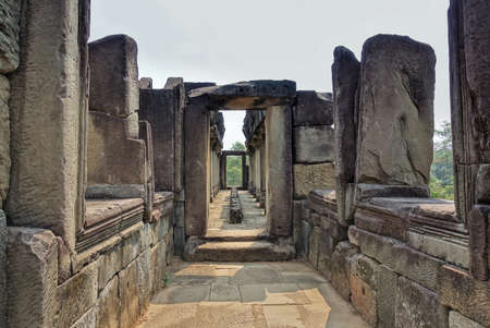 A dilapidated stone corridor at the top of the temple. Doorways, windows, columns are damaged by time. There is no roof. Sunny day. Cambodia. Angkor. Unesco heritage.のeditorial素材