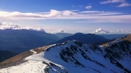 The sun illuminates the top of the Caucasian ridge. There is snow on the slopes. In the distance,...