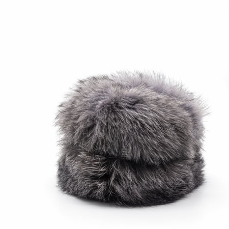 Winter warm women's hat made of bluefrost fur - a hybrid of a polar fox and a silver fox. Thick fluffy fur, black and white hairs. Decorated with a shiny brooch. Isolated on a white background.の写真素材