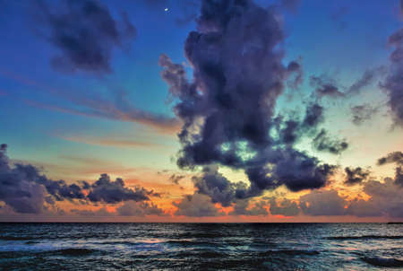 A fantastically bright sunset over the Indian Ocean. There are fancy purple clouds in the blue sky....