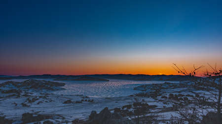 Early morning, dawn begins. The sky above the ridge is colored orange. Reflection of the sun on the...