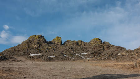 A whimsical mountain range, devoid of vegetation, against the backdrop of a blue sky. Cracks on the stones, yellow lichens. Some snow on the ground. Winter sunny day. Baikal.の写真素材