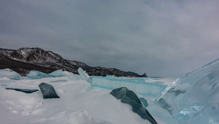 Blocks of ice hummocks on a frozen and snowy lake. Turquoise shiny ice floes close-up. Mountain...