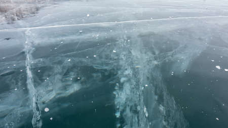 Ice surface close-up, detailed. Deep intersecting cracks, frozen bubbles are visible on the turquoise ice. Lake baikalの写真素材