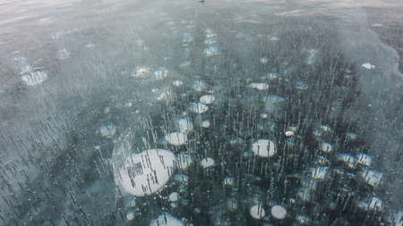 Transparent turquoise ice, close-up. Full screen. Cracks on the surface. Bubbles of frozen methane...