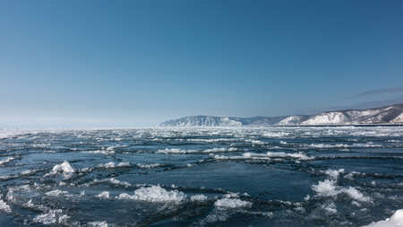 Ice drift on the river. Blue ice floes and melted snow on the surface of the water. Snow-covered...