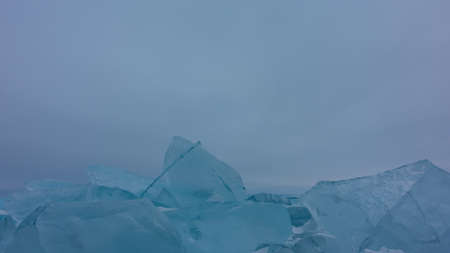 Turquoise ice floes and hummocks against the foggy sky. Bizarre shapes, sharp edges. Close-up. Copy space. Lake baikalの写真素材