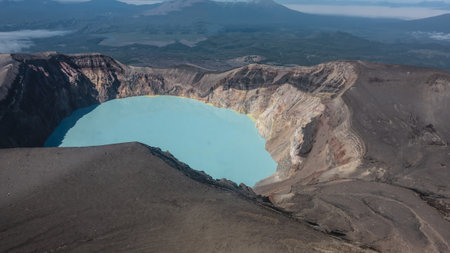A lifeless acid lake in the crater of a volcano. Sulfur deposits on turquoise water. Multi-layered slopes of beige shades. Reflection and shadows on the surface. View from a height. Kamchatkaの写真素材