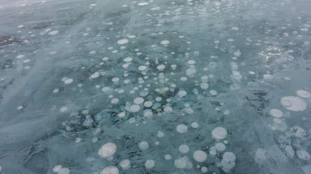 Turquoise ice, close-up. Full screen. Intersecting cracks are visible on the surface. Columns of...