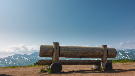 On the observation deck there is a low bench made of unpainted logs. Some grass on the ground....