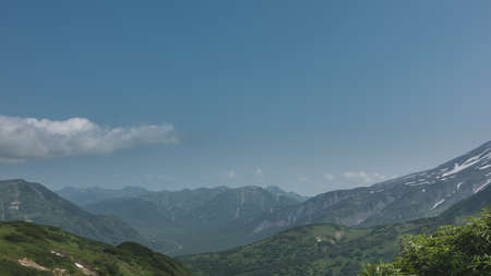 The mountains are covered with green vegetation. The ridge extends to the horizon. A river meanders in the valley. Cumulus clouds in a blue sky. Copy space. Kamchatkaの写真素材