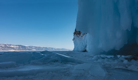 The base of the rock is covered with thick layers of splashes and icicles. Blocks of ice on a frozen...