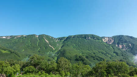 A picturesque mountain range against a clear blue sky. There is lush green vegetation on the slopes. The forest is at the foot. copyspace. Kamchatkaの写真素材