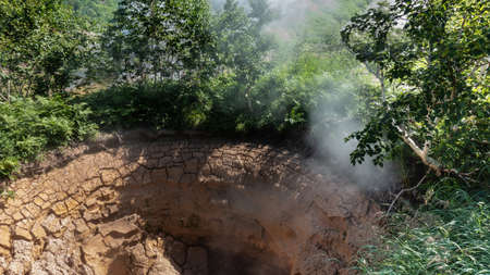 Geyser - a mud pot. close-up. Hot steam rises from the center. Cracks on the clay edges. There is...