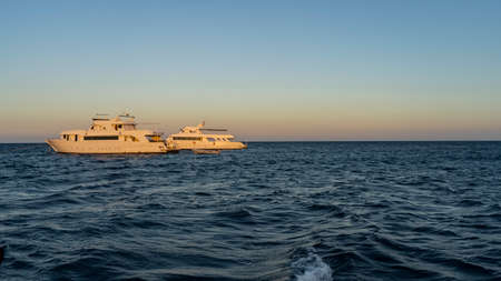Two white yachts in the Red Sea are illuminated by the evening sun. Ripples on the blue water. clear...