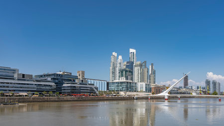 The city quarter of Puerto Madero Buenos Aires. Above the river is a beautiful swing Women bridge - Puente de la Mujer. Skyscrapers against the blue sky. Argentinaの写真素材