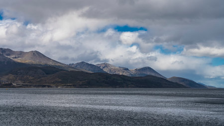 A picturesque coastal mountain range against a background of blue sky and clouds. Ripples on the surface of the water. beagle channel. Argentina.の写真素材