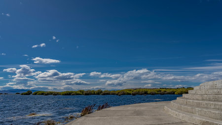 Oval-shaped staircase with concrete steps descends to the lake from the embankment. Ripples on the...