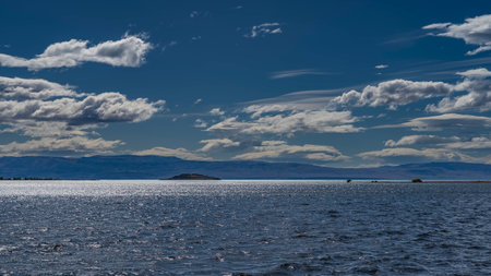 beautiful blue lake. Ripples and sun glare on the surface of the water. A mountain range is visible...
