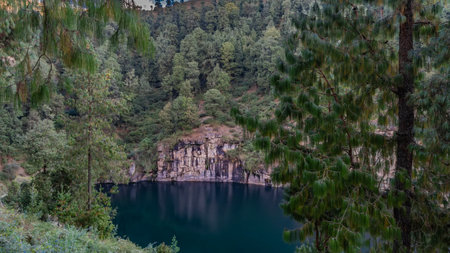 An amazing emerald lake in the crater of an extinct volcano. The steep rocky shores are reflected on...