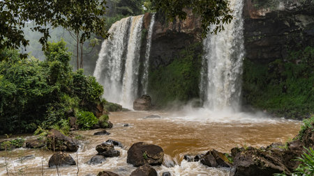 Beautiful tropical waterfalls fall from the cliff into the river. Splashes. picturesque boulders in the riverbed. Lush green vegetation. Iguazu Falls. Two sisters. Argentina.の写真素材