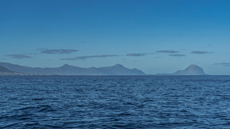 The endless blue ocean. Ripples on the surface of the water. A picturesque mountain range against the background of the sky and clouds on the horizon. Mauritius. Islandの写真素材