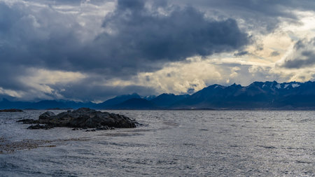 A tiny rocky islet in the ocean. Ripples on the water, algae on the surface. In the distance, the...