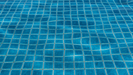 A fragment of a swimming pool. The blue tiled bottom is visible through the clear water. Wavy...
