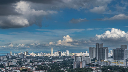 The city's panoramic landscape. The view from the height. Buildings among the green vegetation. Skyscrapers, towers against a blue sky and clouds. The ocean is far away. Malaysia.の写真素材