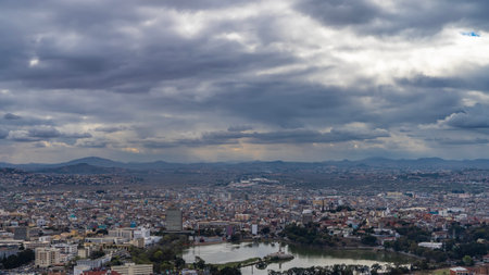 Panorama of the city from a height. There are many multi-storey buildings, a calm urban lake, and...