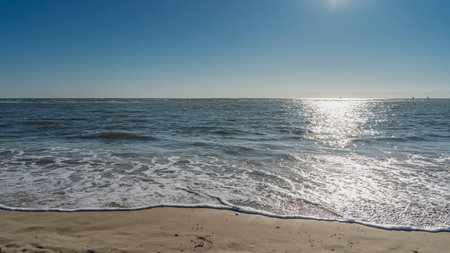 Seascape. Delicate foam of waves on a sandy beach. A sunny path on the surface of the water. The blue ocean. Azure clear sky. Copy space. Madagascar. Morondava. Mozambique Channelの写真素材