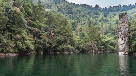 The beautiful lake is surrounded by mountains. Green forest on the slopes. A picturesque pillar-shaped rock rises above the emerald water. Reflection.の写真素材