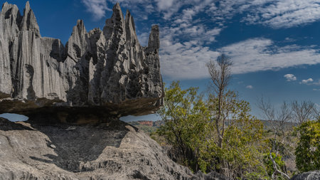 Bizarre karst rocks against a background of blue sky and clouds. Steep furrowed slopes, sharp spiny...