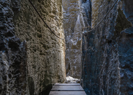 A narrow passage between steep cliffs. Safety ropes on steep rough slopes. A boardwalk. Rock ahead. Madagascar trekking. Tsingy De Bemarahaの写真素材