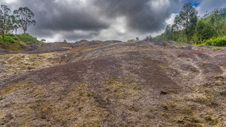 The unique landscape of Mauritius, 23 colored earth. Colorful sand hill. Green vegetation on the slope. Blue sky, dark clouds. La VallÃ©e Des Couleurs Nature Parkの写真素材