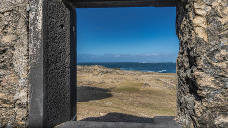 Seascape framed by old weathered stone walls. The waves of the blue ocean are foaming. Azure sky, clouds. Sparse grassy vegetation on the coast of the island. Mauritius. Lighthouseの写真素材