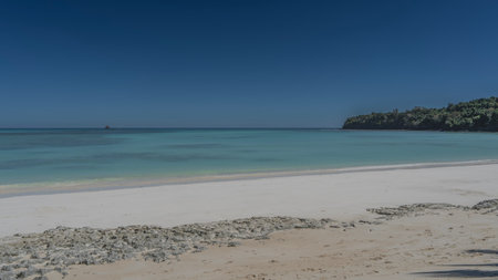 A beautiful beach on a tropical island, without people. Calm turquoise ocean, white sand, clear blue sky. A green hill in the distance. Copy space. Madagascar. Nosy Iranjaの写真素材