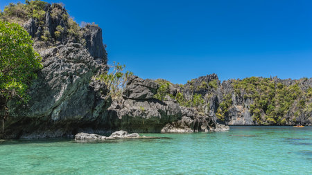 The beautiful turquoise lagoon is surrounded by cliffs. Green tropical vegetation on steep slopes. A...