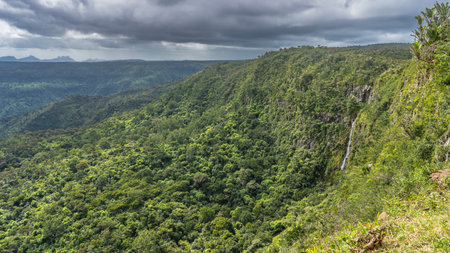 Endless mountain landscape. The waterfall flows down the slope among the lush green vegetation....