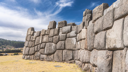 The wall of the ancient Inca fortress Sacsayhuaman. Amazing unique stonework. Ashlar polygonal masonry. Boulders are closely adjacent to each other. The grass in the clearing.の写真素材